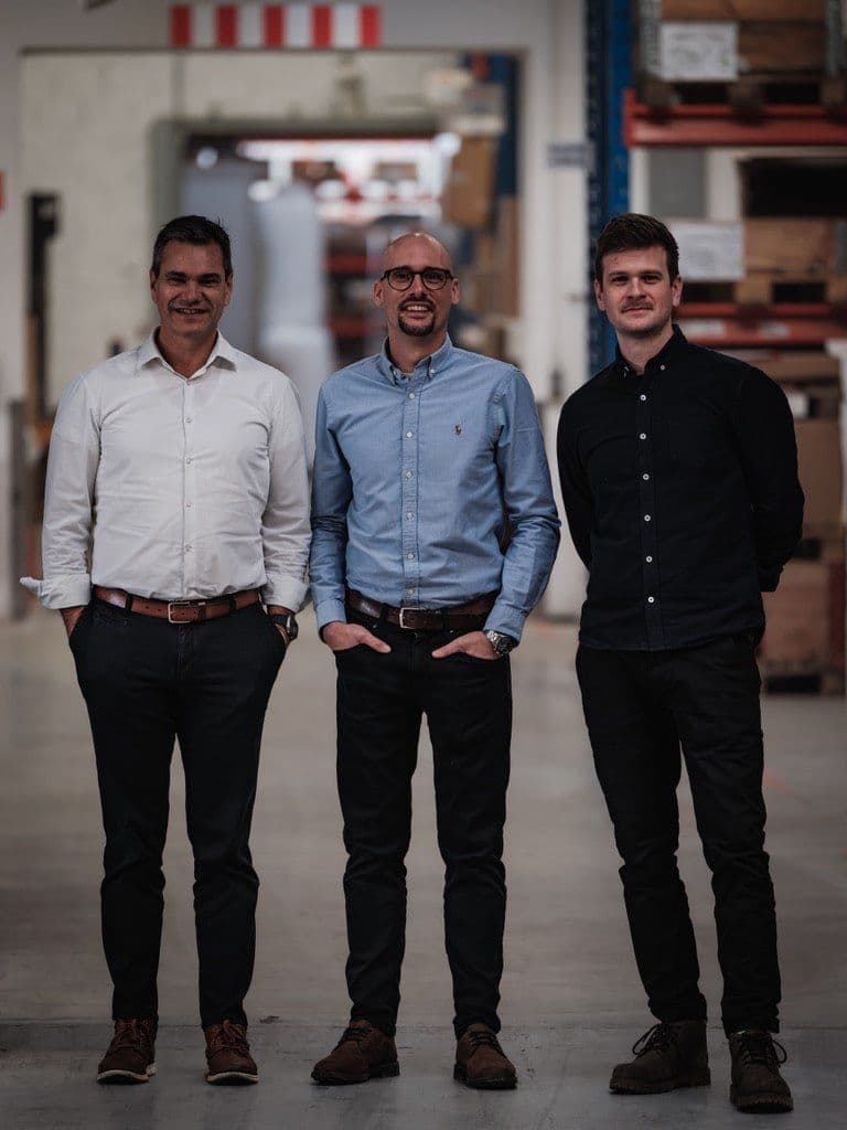 Die Gründer Wolfgang Auer, Christoph Reiter und Julian Kranner stehen in einer Lagerhalle