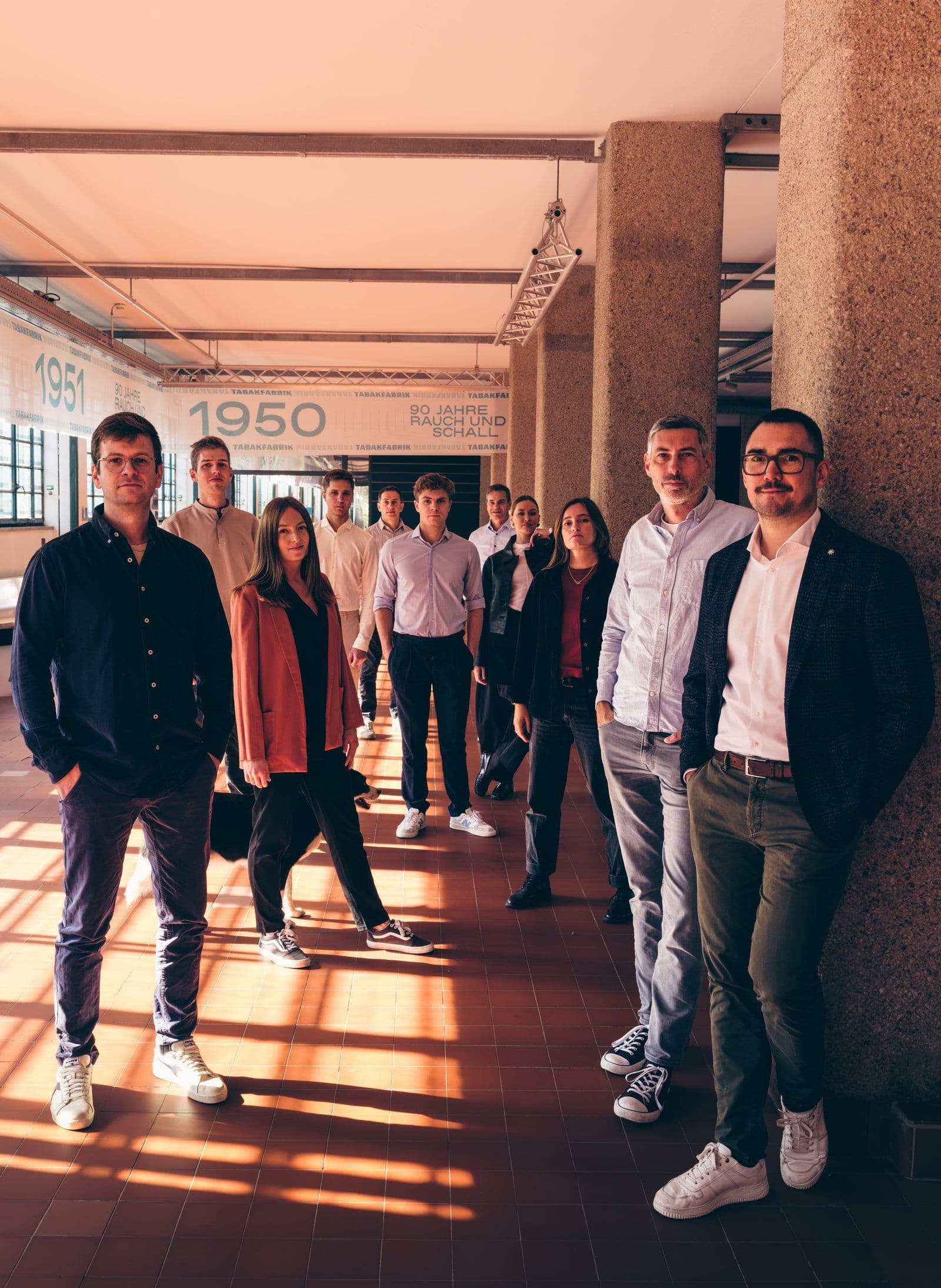 Das Team von Minotera steht gestaffelt in der Säulenhalle der Tabakfabrik Linz