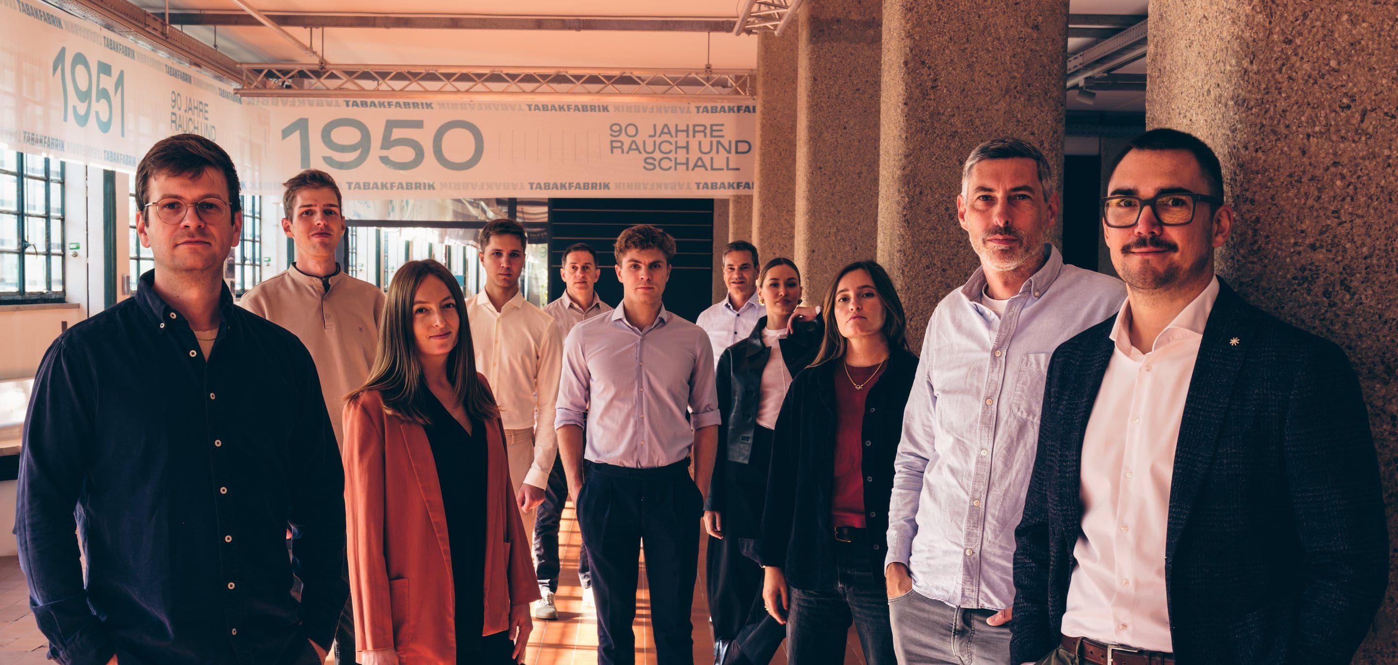 The Minotera team stands staggered in the columned hall of the Tabakfabrik Linz